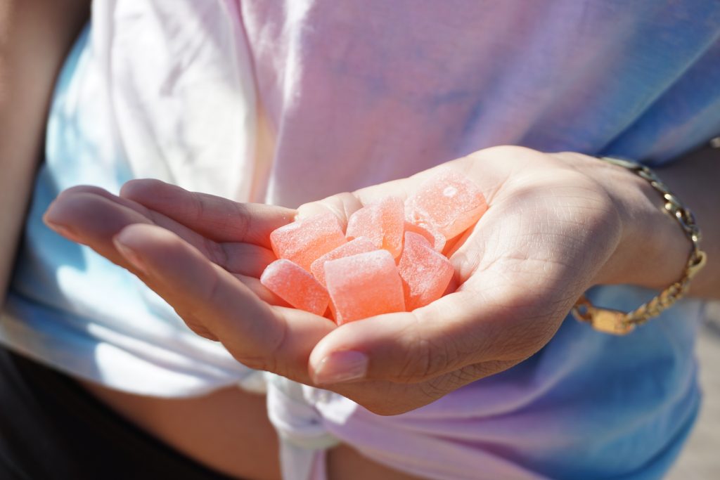 Image of a hand holding delta-8 gummies thc pink bracelet different